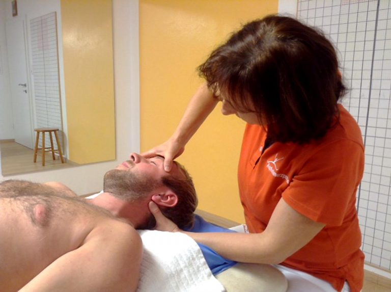 Physiotherapeutin Antonia Reschenhofer behandelt einen Patienten mittels einer Kopf- und Nackenmassage.